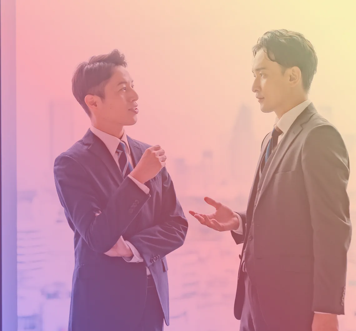 窓辺で向き合って話し合う2人のビジネスパーソン